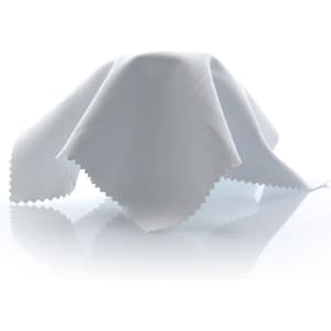 A white cleaning cloth with a scalloped edge, resting on a reflective surface. It features a logo.