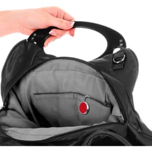 A black handbag interior with a silver key hanger and a red accent, being held by a hand.