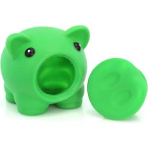 A green pig-shaped money box with a removable lid and circular slot for coins. It features large, cute eyes.