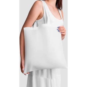 A woman holds a large, plain white reusable grocery bag with shoulder straps. The bag has a logo on it.