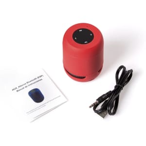 A red Bluetooth speaker accompanied by a charging cable and a manual. The speaker features control buttons on top.