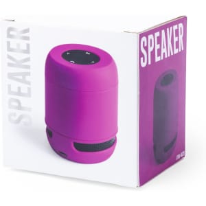 A pink speaker in a box, featuring a circular top with control buttons and a mesh base. The box has a logo.