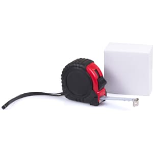 A black and red tape measure next to a white cube, featuring a textured grip and a logo.
