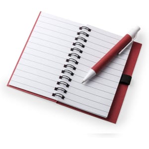 A red notebook with spiral binding and lined pages, accompanied by a white pen.