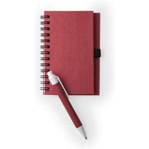 A red spiral-bound notebook stacked with a matching red pen, featuring a black elastic band.