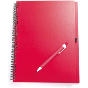 A red notebook with a spiral binding and a matching red pen placed on top. The notebook has a cover and a logo.