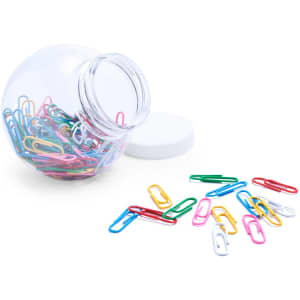 A clear jar filled with assorted coloured paper clips, with some clips scattered on the surface beside it.