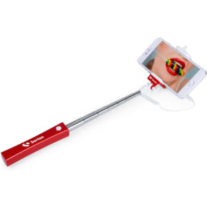 A red selfie stick with a phone mount, extending from a metal handle, holds a smartphone displaying a close-up image.