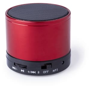 A round red speaker featuring a black speaker mesh top and control buttons along the base. It includes a branding logo.