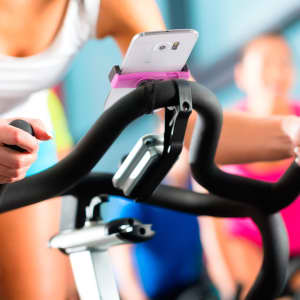 A car phone holder in pink, securely holding a smartphone on a bike handlebar.