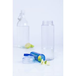 A clear drink bottle with a blue lid and a logo, accompanied by lime halves on a white surface.