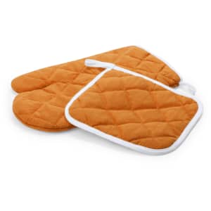 A set of orange quilted oven mitts and pot holder, featuring white trim. The set has a logo on it.