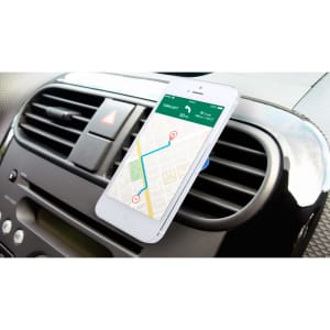 A white smartphone is mounted on a car dashboard, displaying a map with a route. The dashboard features air vents and controls.