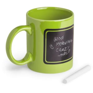 A green mug with a chalkboard surface and a white piece of chalk beside it. It also has a handle and a logo.