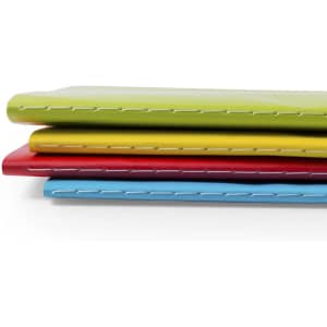 A stack of four colourful notebooks in green, yellow, red, and blue, featuring visible stitching along the edges.
