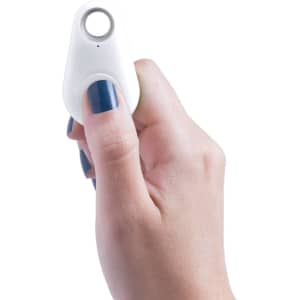 A white tracking device held in a hand with blue nail polish, featuring a circular button and a small light.