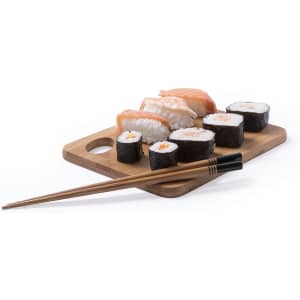 A set of wooden chopsticks alongside an assortment of sushi on a wooden board. The chopsticks are a light brown.