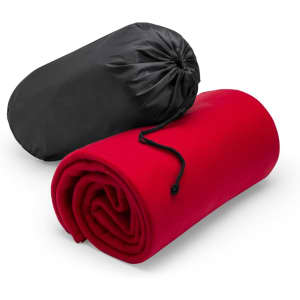 A rolled red blanket with a black carry pouch, featuring a drawstring closure.