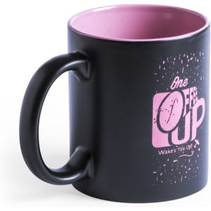 A black coffee mug with a pink interior and a graphic design. It features a handle and has a logo.