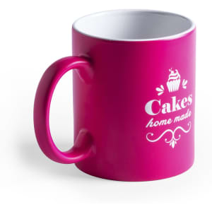 A pink coffee mug with a white interior and a branding logo featuring a cupcake design.