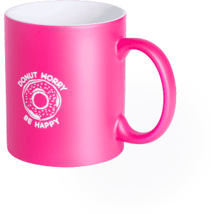 A pink coffee mug with a logo featuring a donut and the phrase "Donut Worry Be Happy."