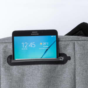 A grey Nevium backpack with a black zippered pocket holding a tablet. The backpack features a logo on its surface.