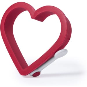 A red heart-shaped mold with a white handle, designed for creating heart-shaped items.