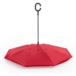 A red reversible umbrella with a black C-shaped handle, displayed opened and showcasing its eight-panel design.