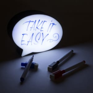 A glowing speech bubble message board in white, alongside four colourful markers.