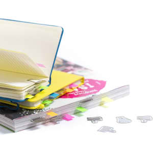 Multiple items including a blue, yellow, and white binder with colourful tabs and silver clips on a stack of magazines.