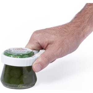 A jar opener with a white handle, being held by a hand, designed for easy access to jar lids.