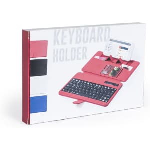 A pink keyboard holder with compartments for a phone and cards, displayed in a box with black, white, and blue options.