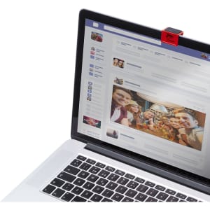 A red webcam cover attached to a laptop, with a group photo displayed on the screen. The laptop is open on a desk.