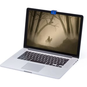 A silver laptop with a blue webcam cover on top, displaying a foggy forest scene on its screen.