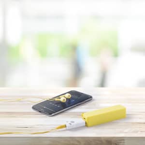 A yellow Bluetooth receiver is placed next to a phone with yellow earphones, set on a wooden surface.