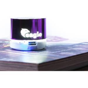 A purple and white portable speaker with a logo, placed on a book.