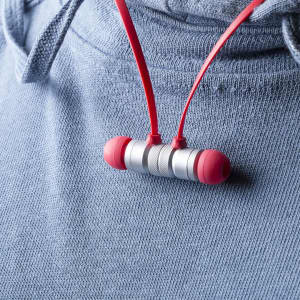 Red and silver Voltar earphones hanging from a grey hoodie. The earphones have a sleek design and a logo visible.