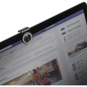 A black webcam cover joystick attached to a computer screen, with a blurred interface visible behind it.