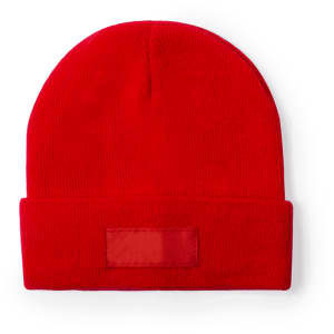 A red beanie hat with a folded cuff and an empty logo patch on the front.