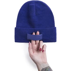 A blue beanie held in a hand, featuring a textured fabric and a small branding patch.