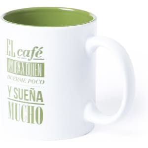 A white coffee mug with a green interior features decorative text and has a handle.