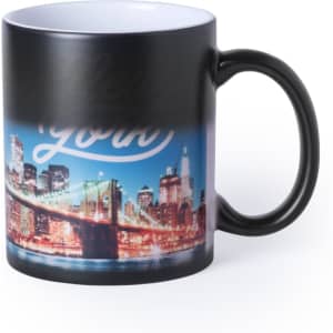 A coffee mug featuring a vibrant night cityscape of New York with a black exterior and a white interior.