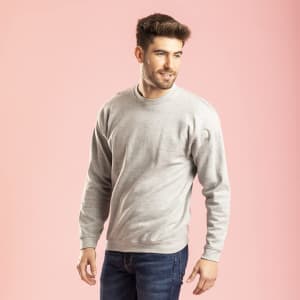 A grey adult sweatshirt on a male model, set against a pink background. The sweatshirt features a small logo.