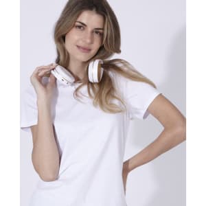 A woman poses in a white t-shirt with white headphones resting around her neck.