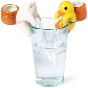 A glass filled with water features quirky animal-shaped straws in the form of a cat and a duck.