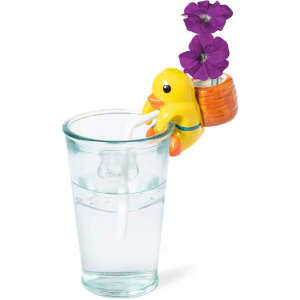 A yellow duck-shaped flowerpot with purple flowers on the side of a clear glass filled with water.