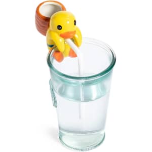 A yellow duck-shaped drink bottle holder with a straw, sitting on the rim of a clear glass filled with water.