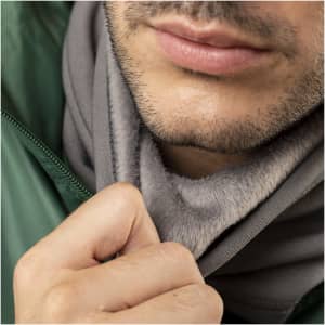A grey neck warmer and hat displayed on a person, featuring a soft texture and attached to a green jacket.
