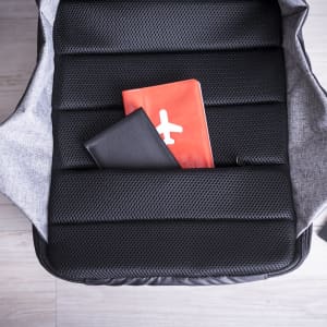A grey and black backpack featuring padded compartments, with a red notebook and a black folder inside.