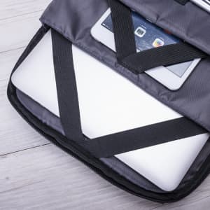 A grey backpack interior featuring a secured laptop and tablet, with black straps for added protection.